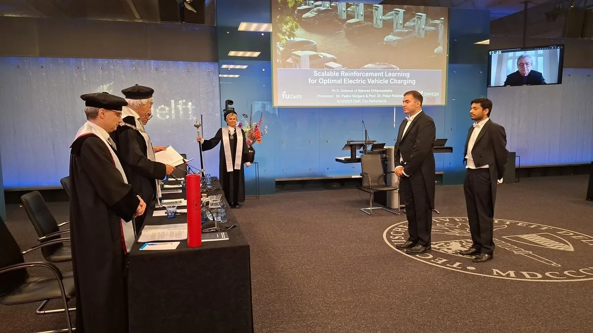 PhD defense ceremony at TU Delft: Stavros Orfanoudakis stands before the doctoral committee, with the thesis title on screen